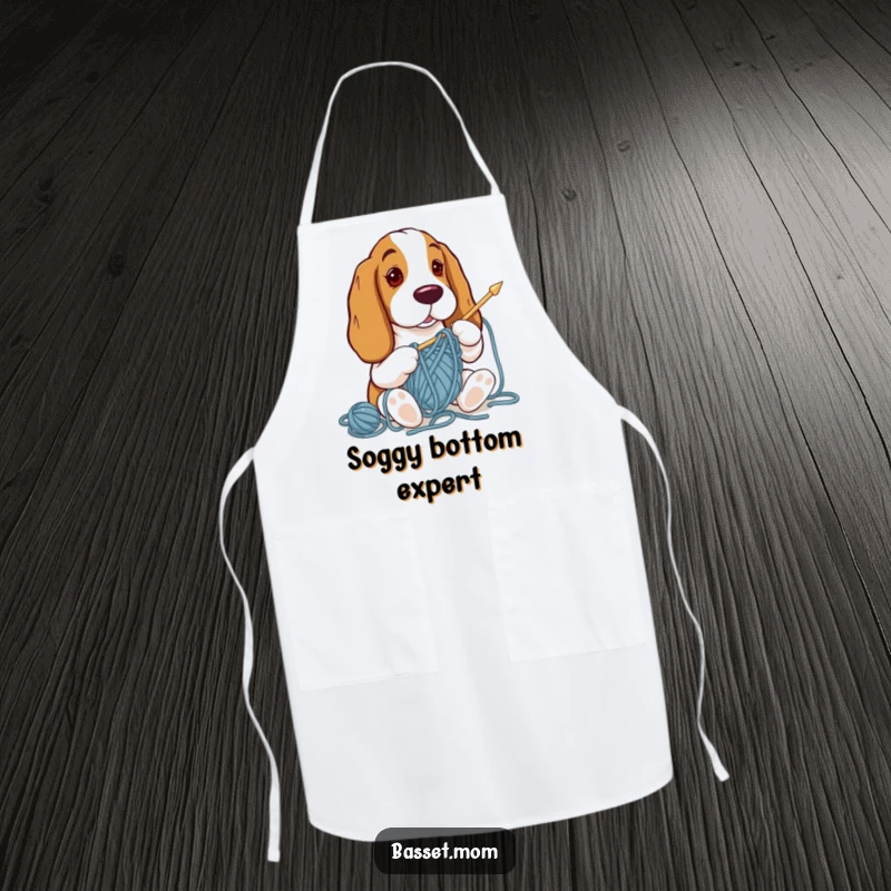 Funny Basset Hound apron featuring a dog tangled in yarn while trying to knit, protecting the wearer from spills.