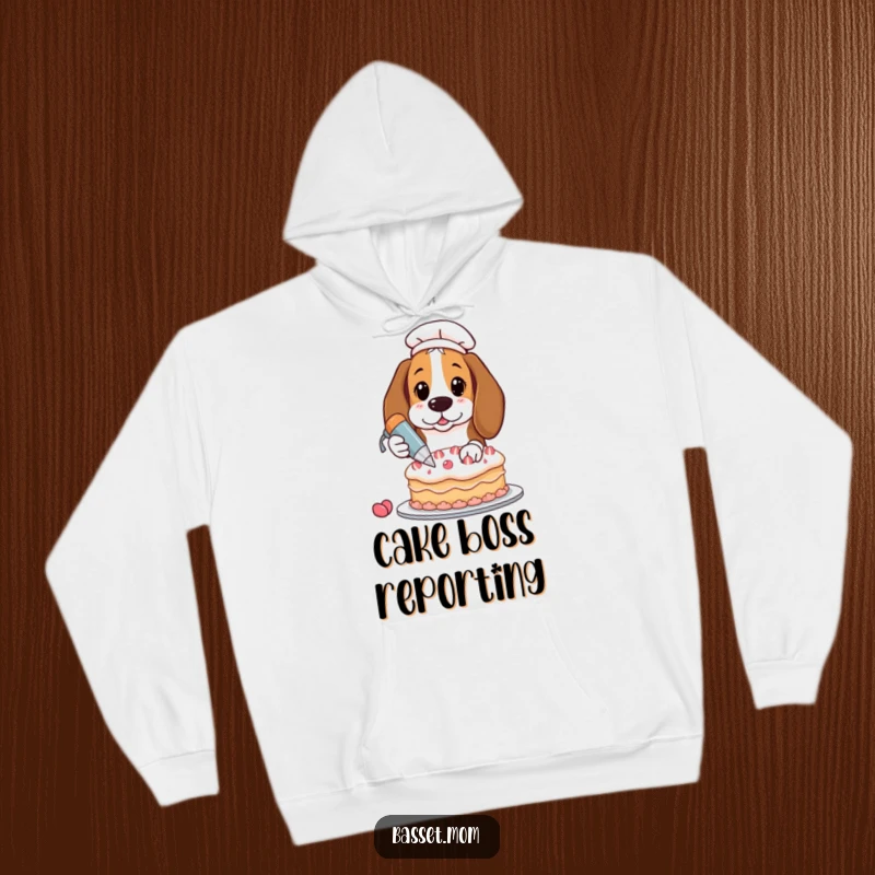 Funny Basset Hound decorating a cake, wearing an apron, soft hooded sweatshirt, humorous pet gift.