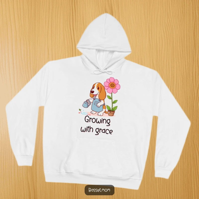 Funny Basset Hound hoodie depicting a dog in a gardening apron watering a giant flower, ideal for cozy garden days.