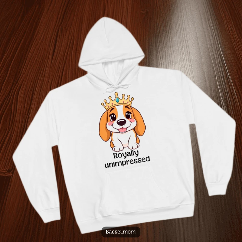 Funny Basset Hound wearing a crown poses regally with a smile, featured on a warm hoodie, offering cozy comfort and royal humor.